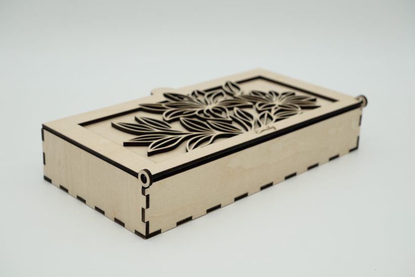 Holzkiste mit dekorativem, eingraviertem Blumenmuster auf dem Deckel. Holzkiste mit floralem Design auf der Oberfläche und gestanzten Kanten.