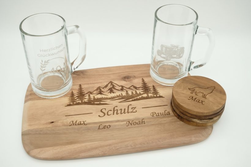 Personalisiertes Holzbrett mit Gravur für Familien | Handveredelt Hamburg Personalisiertes Servierbrett aus Hamburg: Holz mit Lasergravur Familie Schulz, Bergmotiv, passenden Gläsern und Untersetzern.